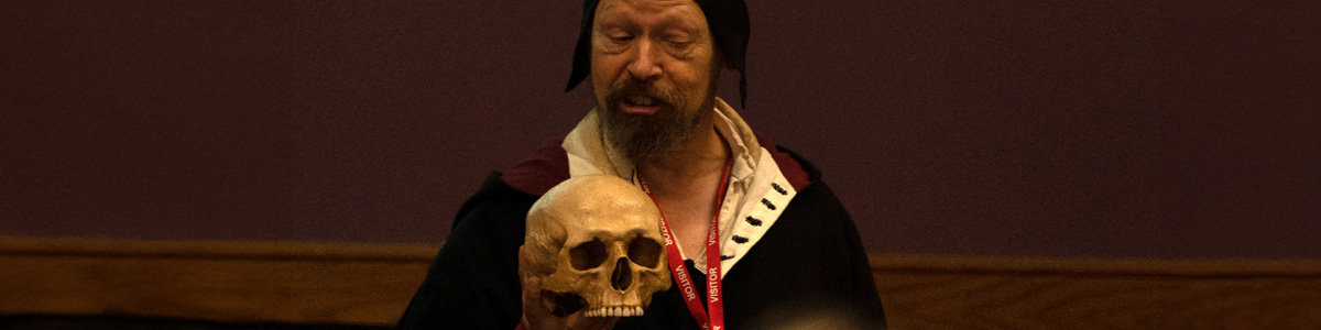 A visitor dressed up in Tudor Alchemist holding a skull