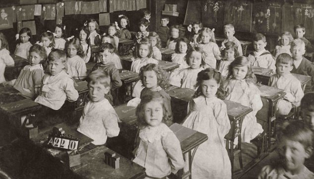 Edwardian or Victorian infants sitting at their desks in classroom during a nature lesson using chalk on slate. Early 1900's